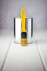 yellow brush with a can of paint on a white wooden background close-up - 519342817