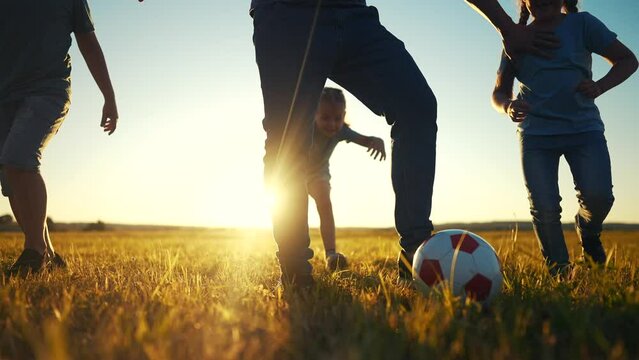 happy family playing a soccer in the park. group of children in nature playing ball with father silhouette park. happy family kid dream concept. funny kids sunlight playing ball on grass in summer