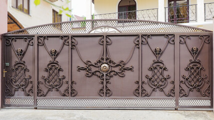 Patterned expensive iron fence of a private house. Villa entrance. Production of forged doors. Reliable property protection.