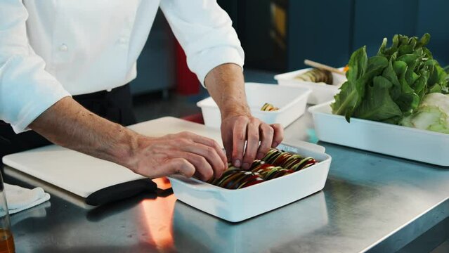 Close-up: The chef is serving ratatouille in a bowl. The process of preparing food in a restaurant.