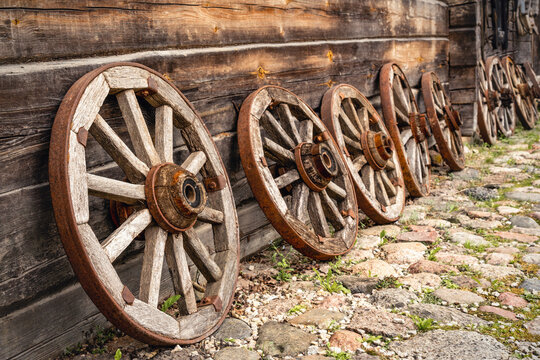Old wooden wagon wheels leaning on a log cabin