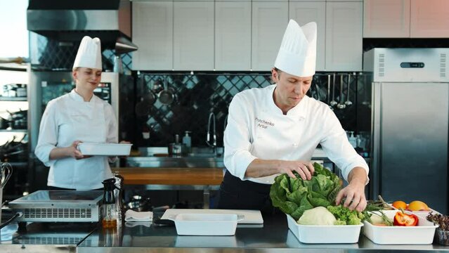 Professional restaurant kitchen, portrait of chefs Men and women: Chef's assistant brings ingredients