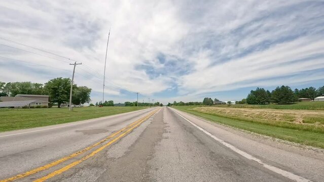 POV while driving on country road through rural Illinois; driving past homes, farms and solar panels; concepts of open road, rural life and transportation