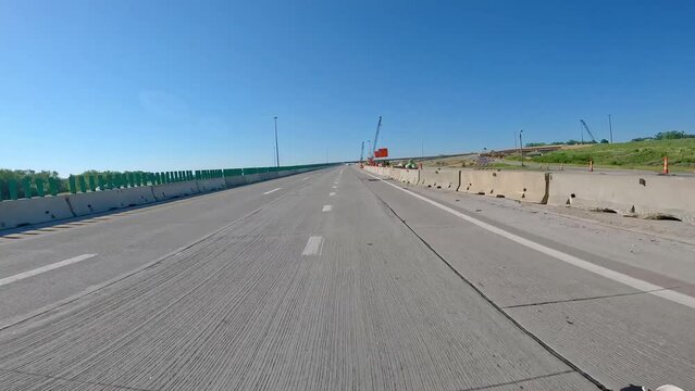 POV driving thru a construction zone with concrete barricades and flyover ramps on a bright sunny day