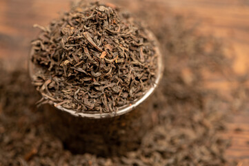 Large-leaf black tea in a glass and scattered on the table. Close-up of the surface texture