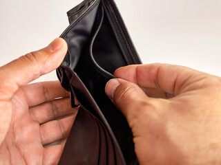 A man looks into an empty wallet on a white background.