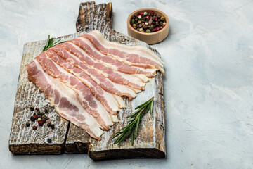 Raw bacon, bacon strips meat slice thin slicing pork fat meal on a light background, ketogenic diet, place for text, top view
