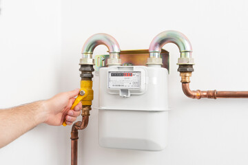 Picture of man opening the gas valve. Gas meter in private house. High costs of gas.