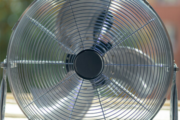 Close up of a big metal fan on the windowsill.