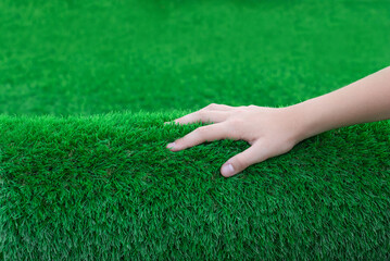 Close-up of a hand stroking a roll of soft artificial turf. Nice touch of clean and antibacterial...