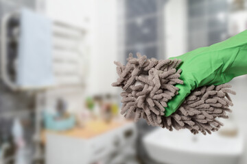 Woman's hand in protective glove with the rag at the bathroom.