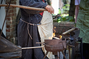 A closeup of a blacksmith fanning a flame