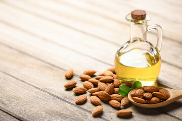 Almond oil with almond nuts on wooden table.