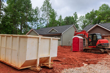 An industrial dumpster rubbish removal containers on the ground beneath a house in construction site