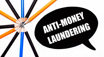 On a light background, multi-colored pencils and on a black background a white card with the text ANTI-MONEY LAUNDERING