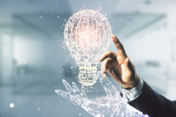 Man hand working with abstract virtual light bulb hologram on blurred office background, idea...