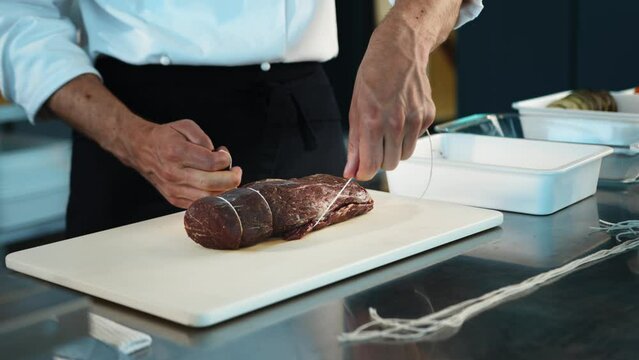 Close-up: The chef cuts the meat of the filet mignon with a knife. The process of preparing food with a restaurant.