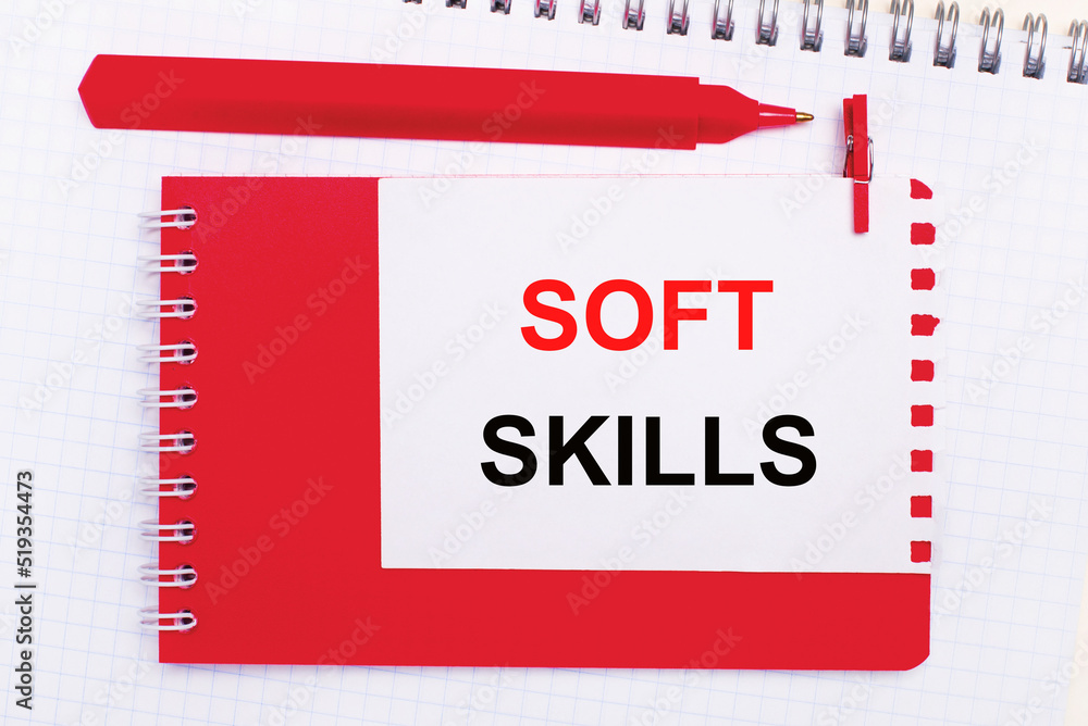 Aufkleber on a white notepad, a red pen, a red notepad and a white sheet of paper with the text soft skills