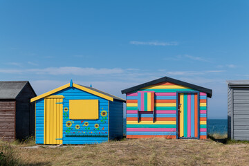 Fototapeta na wymiar 18 July 2022. Hopeman, Moray, Scotland. This is the very colourful beach huts at Hopeman, Moray on a very sunny summers day.