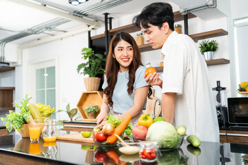 A happy couple prepares and cooks healthy salad with vegetables on a cutting board together in the home kitchen. Food cooking for young couple husband and wife in a good mood and healthy relationship.
