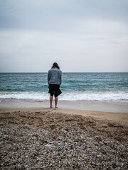 Fototapeta na wymiar junge Frau steht vor Meer auf Strand