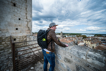 junger Mann mit Rucksack blickt über Arles