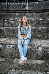 junge Frau sitzt auf alten Treppen und lächelt