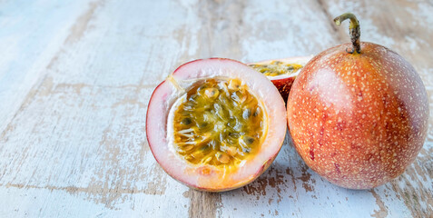 Fresh passion fruit and cut in half slice with green leaves isolated on wooden table background .