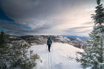Fototapeta premium Active woman, hiking the Dome mountain on a winter day, Charlevoix region, QC, Canada