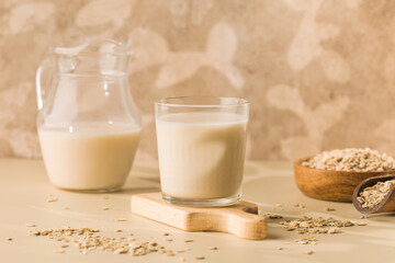 A glass of oat milk, a jug and oat flakes. The concept of alternative lactose-free dairy products. 