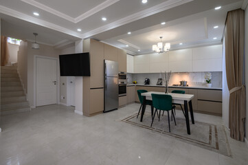 Modern white and beige large luxurious kitchen and dining table in studio apartment