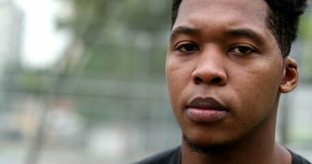 Young African American black man portrait standing outside looking at camera with serious expression