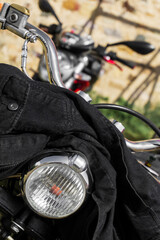Black denim jacket thrown on the handlebars of a motorcycle
