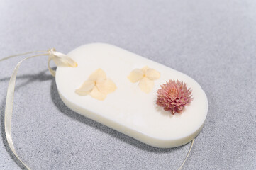 Wax Oval Sachet with Dried Flowers Close-up on Concrete Gray Plane. Product Photo Flat Lay Close-up