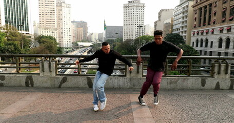 Two male dancers dancing in urban downtown city. Hispanic and African performers dancing