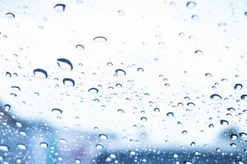 Raindrop texture on car glass against a blue background.