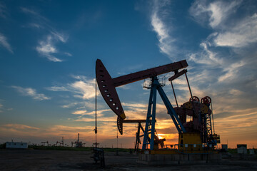 The pumpjack is working at sunset