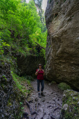Naklejka na ściany i meble Wanderin in der Bürserschlucht, wandernde Frau neben den steilen Felswänden auf dem schmalen Weg durch die bewaldete Schlucht. bei Bürs in Vorarlberg, Österreich