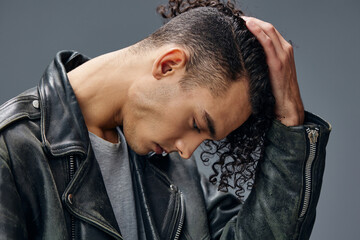 Elegant stylish tanned curly man leather jacket posing isolated on over gray studio background. Cool fashion offer. Huge Seasonal Sale New Collection concept. Copy space for ad. Headshot portrait