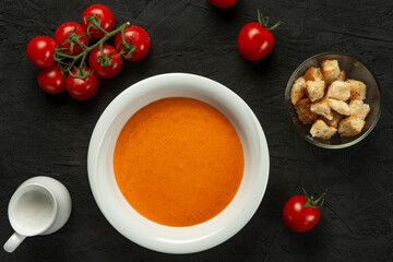 tomato cream soup in white bowl on black desk - Powered by Adobe