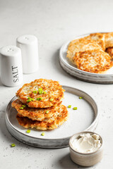 Zucchini pancakes sprinkled with green onions with salt and pepper shaker on white background. Vegetarian food concept