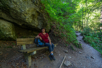 Wanderin in der Bürserschlucht, wandernde Frau neben den steilen Felswänden auf dem schmalen Weg durch die bewaldete Schlucht. bei Bürs in Vorarlberg, Österreich