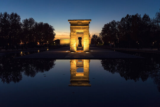 The Debod Temple illuminated at night reflected in the water.