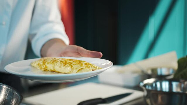 Professional restaurant kitchen, close-up: The chef serves an omelette