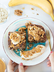 Healthy vegan oatmeal banana bake with rolled oats, walnut, and peanut butter on a plate with a...