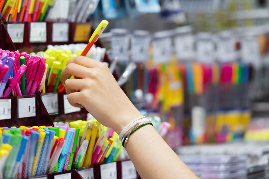 partial view of woman in beaded bracelets near colorful pencils in stationery shop.