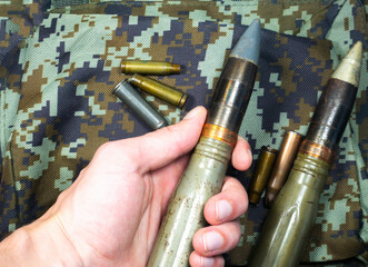 Soldier hold Bullets, shells, cartridges and projectiles on khaki camouflage backpack. Lend-Lease concept. Army concept. Sales of weapons and ammunition. Military industry, war, global arms trade.