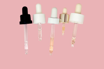 Set of glass pipette with oil, serum and beauty cosmetic product isolated on pink background with copy space. Swatch smear pattern. .