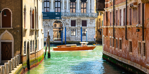 Motor boat flowing through turquoise canals in Venice