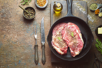 Fresh raw beef steak on wooden board with butter, seasoning and rosemary. Close-up with copy space